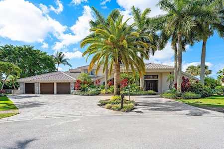 Single-story home with a two-car garage, broad driveway, and mature palm trees.