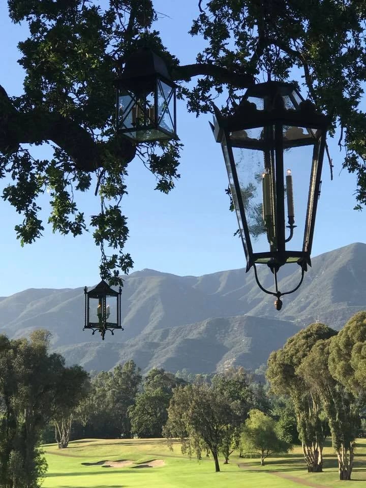 Hanging lanterns frame a manicured golf course and mountain ridges.