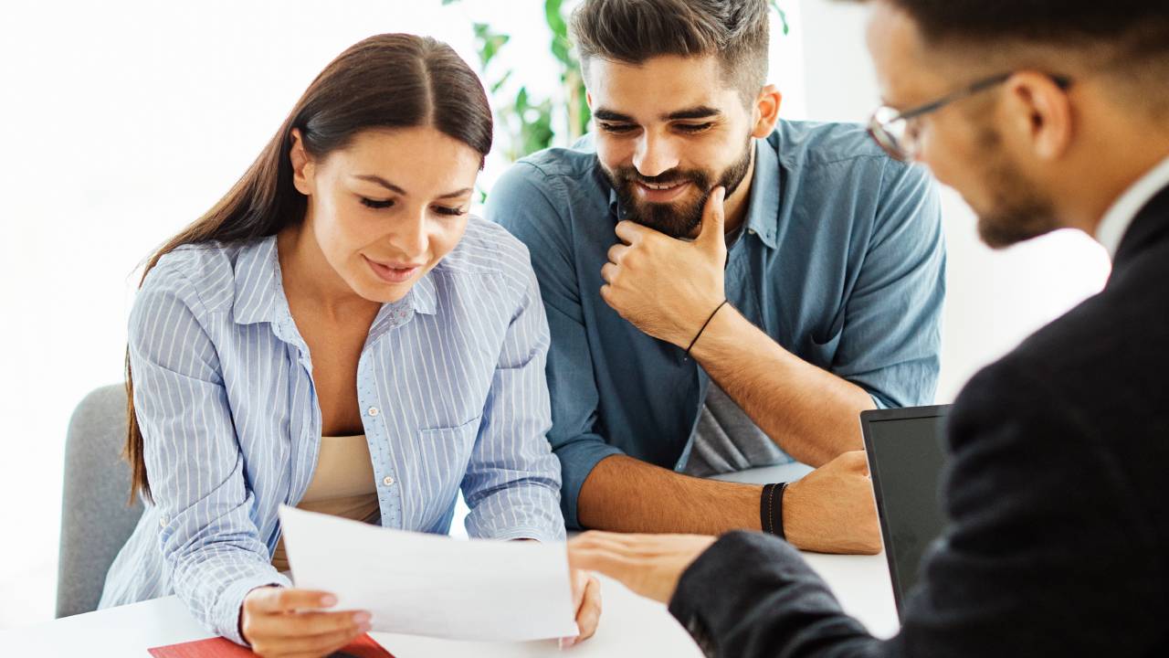 Young couple reviewing paperwork with an agent, discussing options for financing land purchases in Aspen with expert guidance.