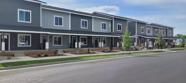 Attached gray townhomes with covered front porches along a residential street.