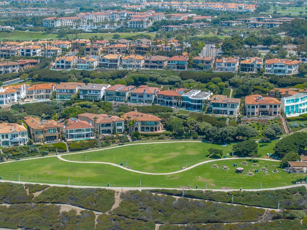 Luxury coastal home aerial view with bright daylight, pristine exterior and scenic ocean backdrop