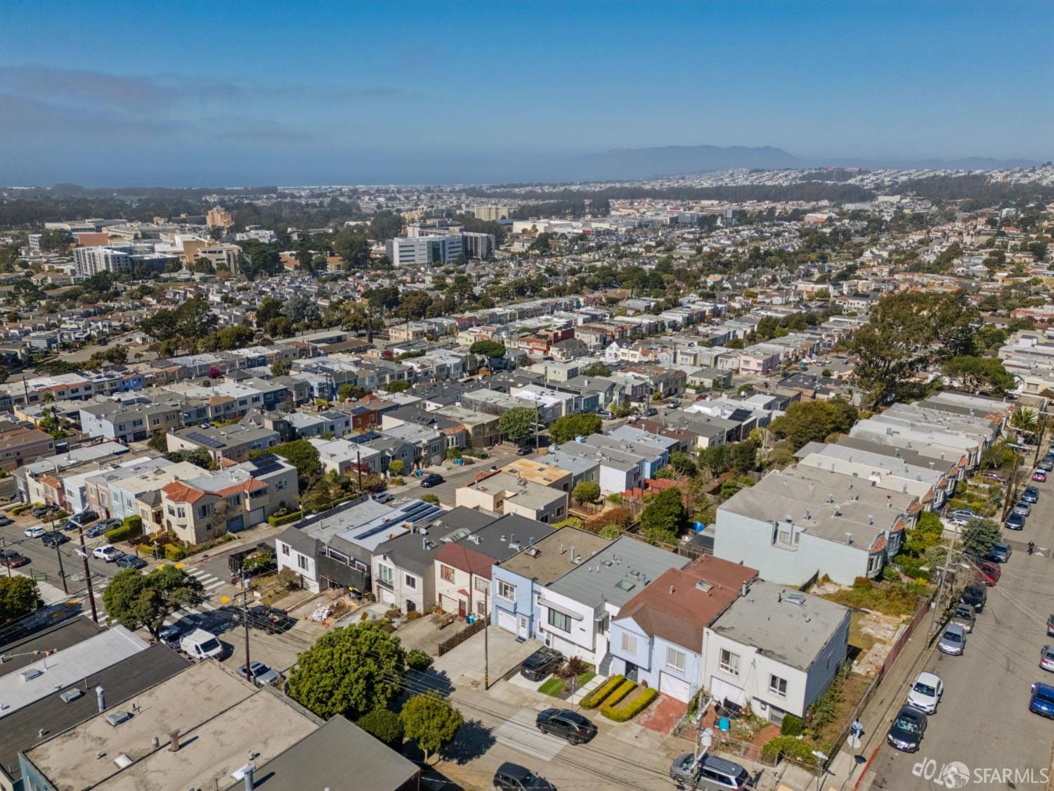 Aerial view of a dense residential neighborhood, with rows of homes and distant hills.