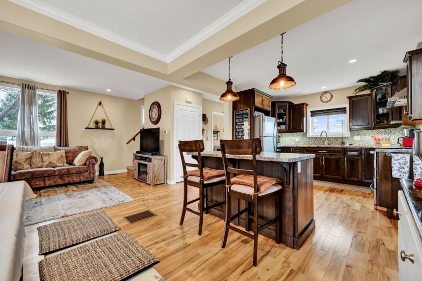 Open-concept kitchen with dark wood island, breakfast bar, hardwood floors, and adjoining living area.