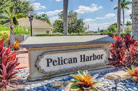 Pelican Harbor entrance sign surrounded by tropical landscaping.