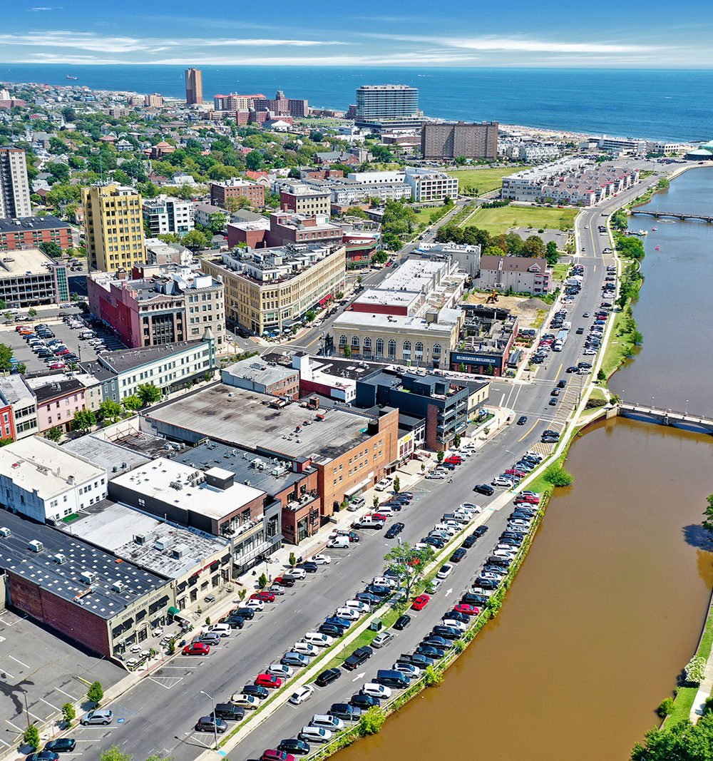 Aerial view of downtown Asbury Park, with the waterfront inlet and Atlantic Ocean beyond.
