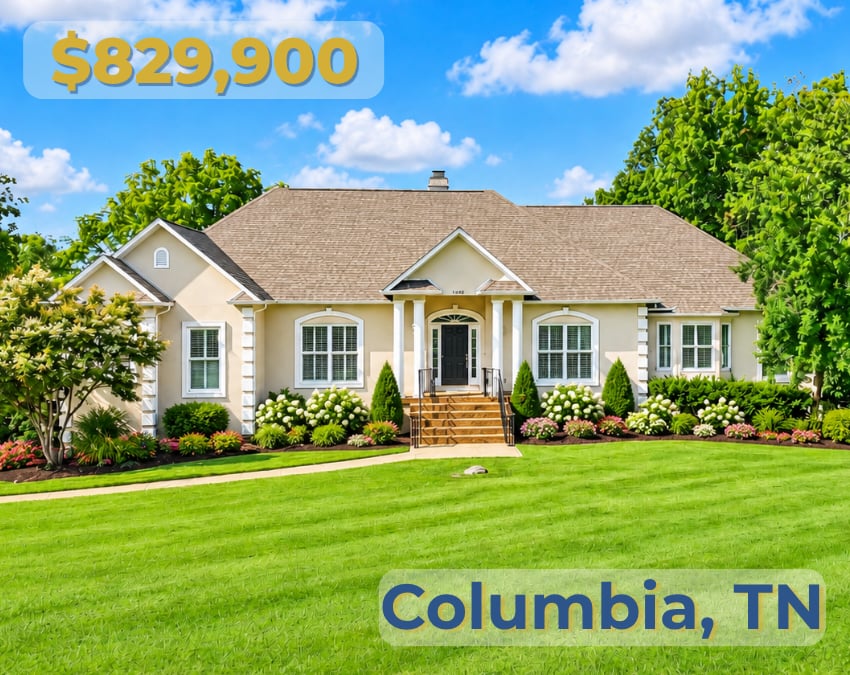 Beige single-story home with a broad shingled roof, landscaped flower beds, and a manicured front lawn.