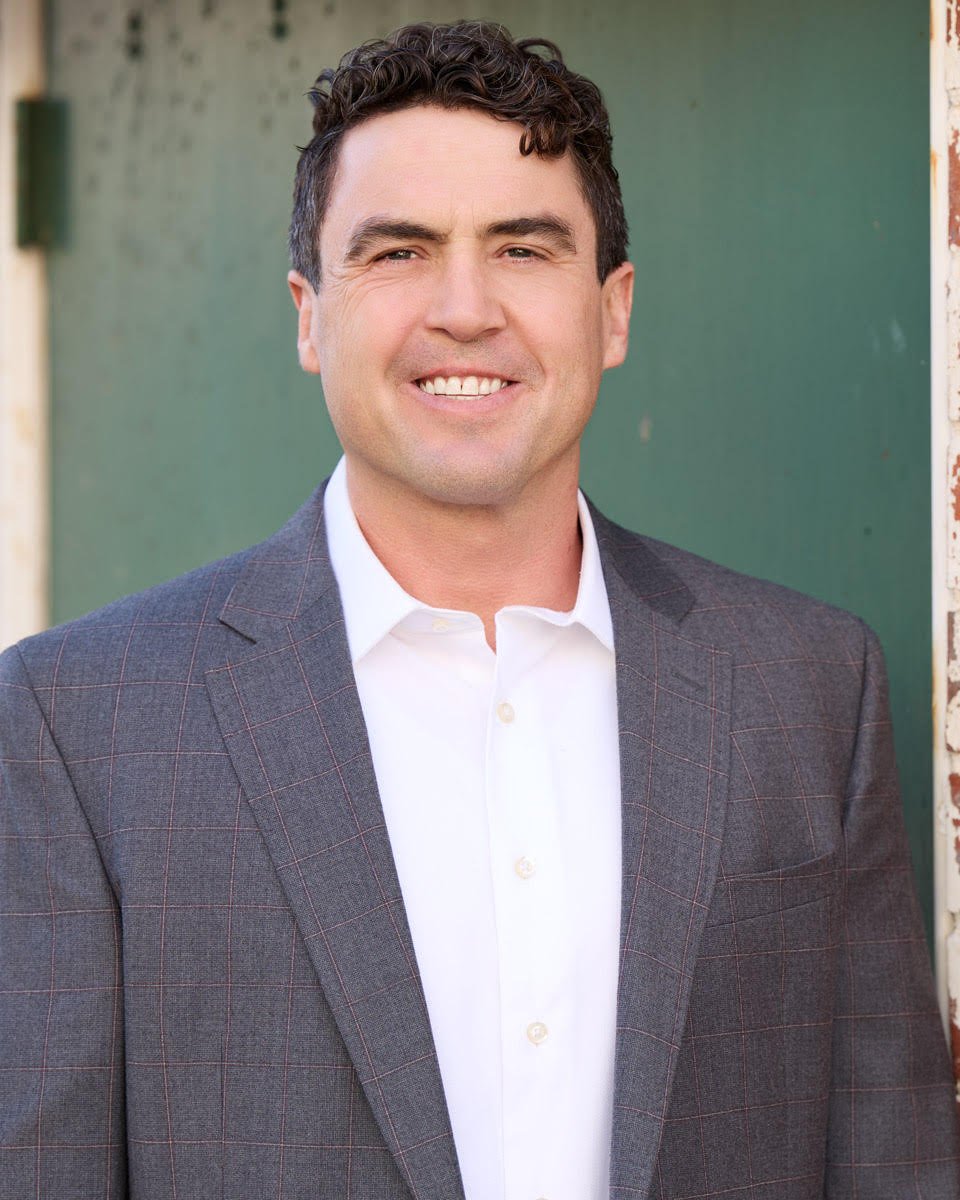 Sky Minor smiles in a gray checked blazer and white shirt.