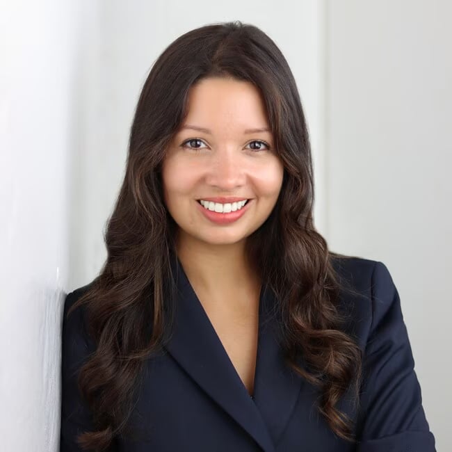Smiling woman with long dark hair wearing a navy blazer.