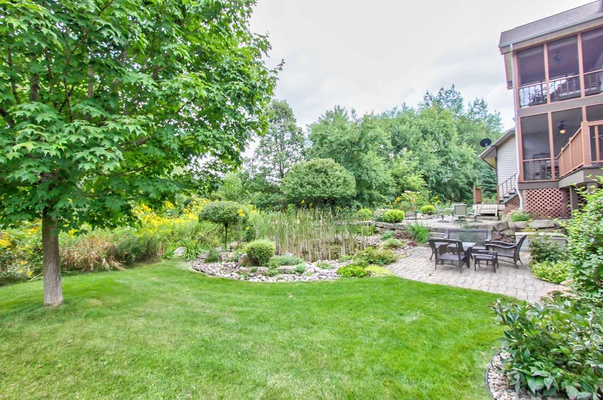 Landscaped backyard with a pond garden and stone patio beside a multi-story home.