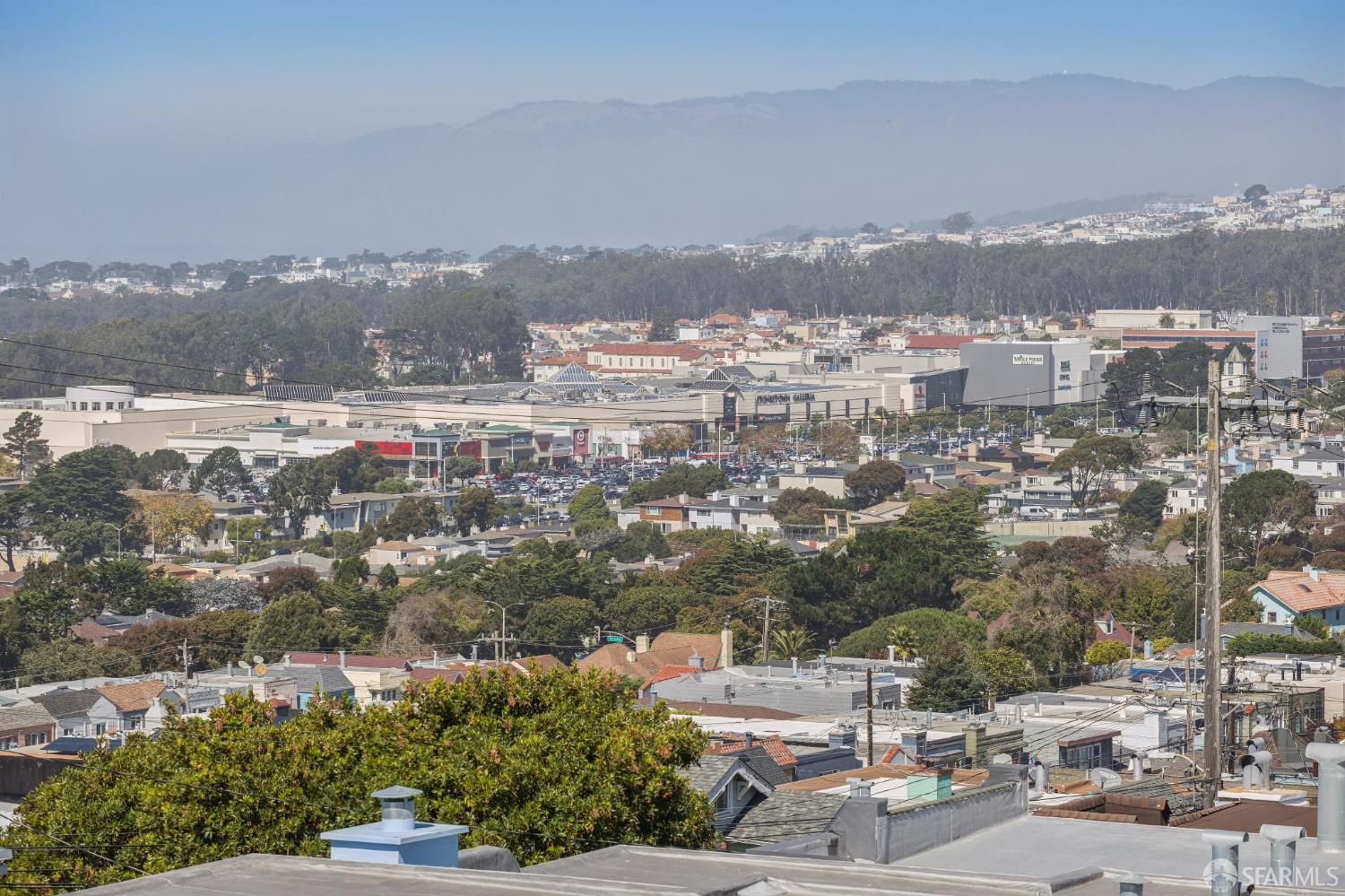 Panoramic neighborhood view with commercial buildings and hazy hills in the distance.