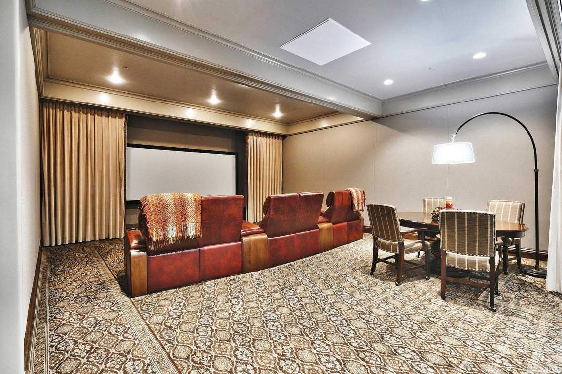 Home theater with red leather seating, a projection screen, and a dining table.