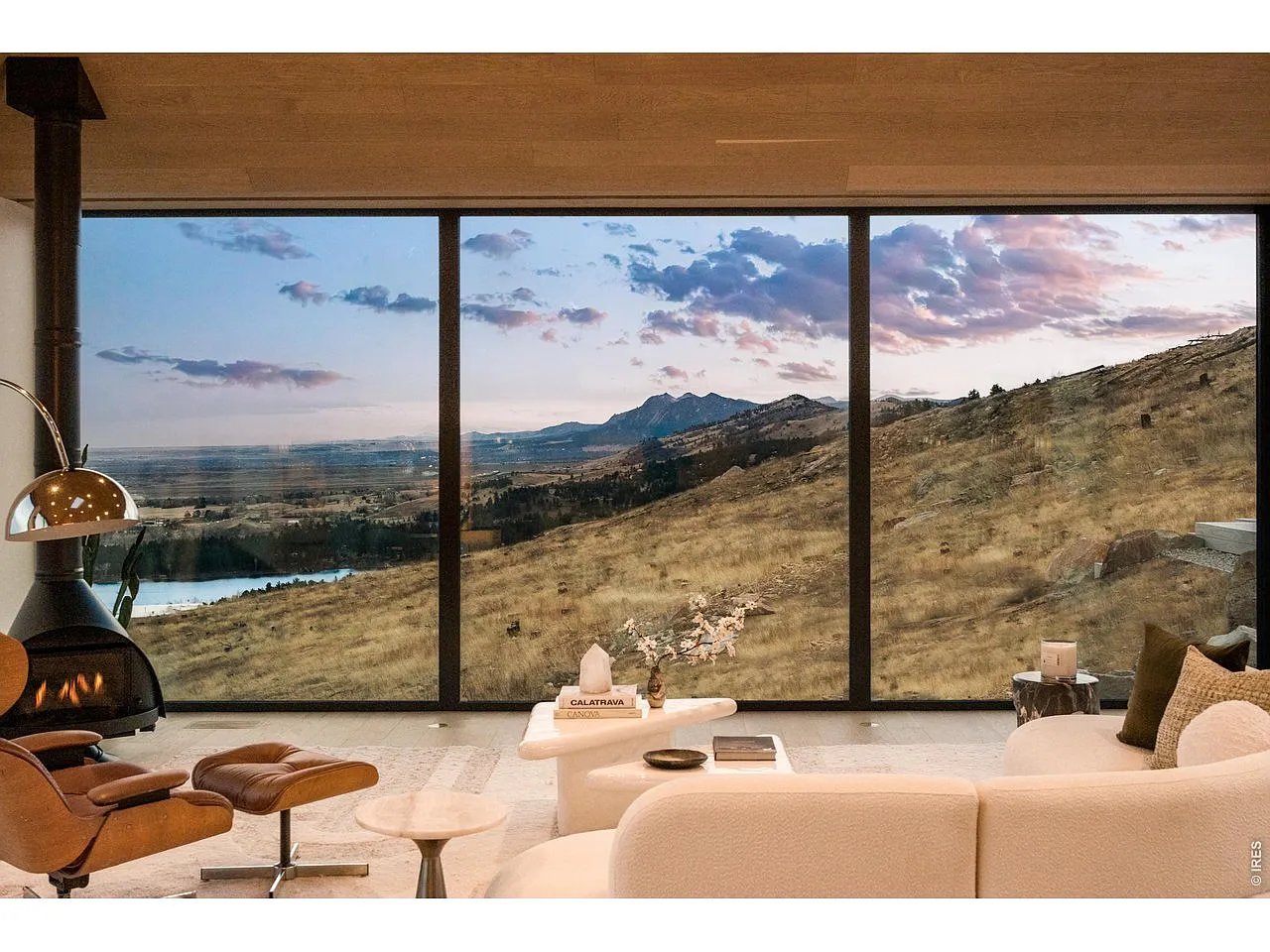 Modern living room with floor-to-ceiling windows overlooking a lake, valley, and mountains.