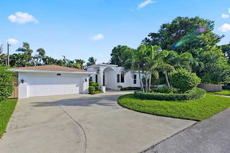 White single-story home with a two-car garage, curved driveway, and palm-lined landscaping.