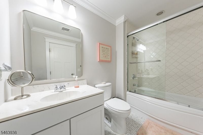 Bathroom with a white vanity, large mirror, toilet, and glass-enclosed tub and shower.