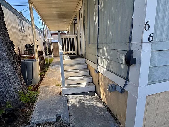 Home entry with covered steps and the number 66 on the wall.