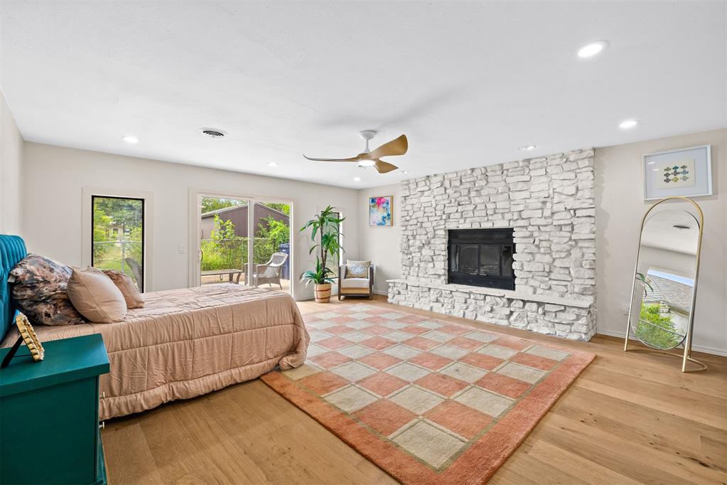 Bedroom with a white stone fireplace, sliding patio doors, and a patterned rug.