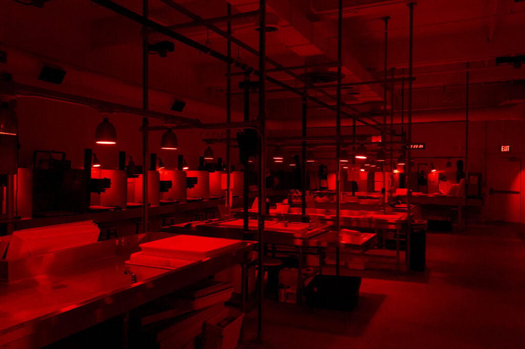 Photography darkroom illuminated with red safelight and equipment stations