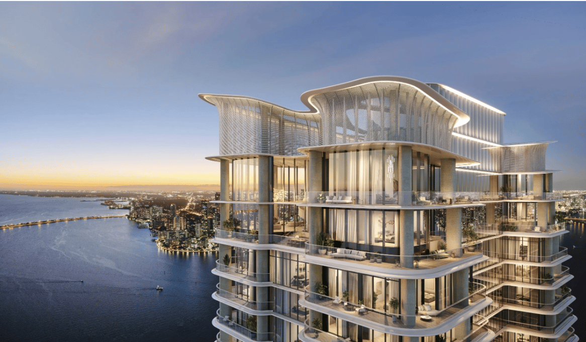 Luxury tower with sculptural roof forms and glass balconies overlooking Biscayne Bay and the Miami skyline at dusk.