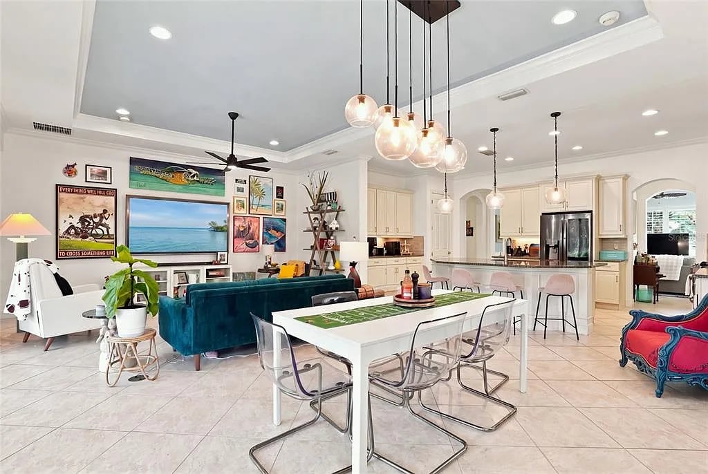 Open-plan living and dining area with a teal sofa, white dining table, and cream kitchen cabinetry.