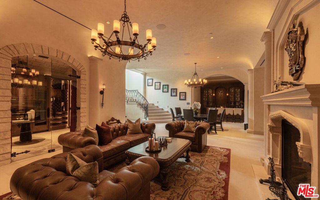 Living room with tufted leather sofas, a stone wine cellar, staircase, and fireplace.