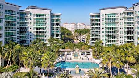 Modern condominiums frame a palm-lined courtyard and swimming pool.