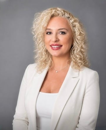 Brittney Lamme in a white blazer against a gray background.