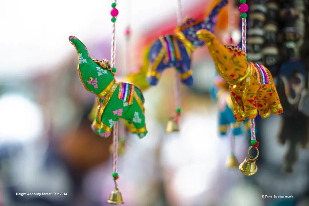 A close-up of colorful, handmade elephant ornaments hanging at a vendor stall during the Haight-Ashbury Street Fair.