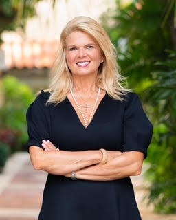 Cari Rentas outdoors in a black dress, arms crossed.