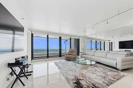 Furnished condo living room with a white sectional and ocean views through floor-to-ceiling windows.