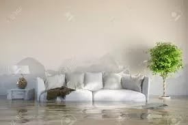Flooded living room with water covering the floor around a white sofa.