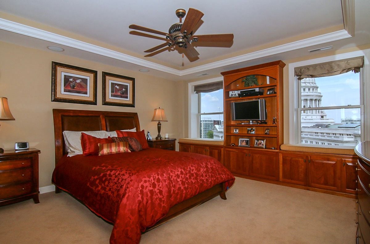 Penthouse bedroom with red bedding, extensive wood cabinetry, and views of the Wisconsin State Capitol.