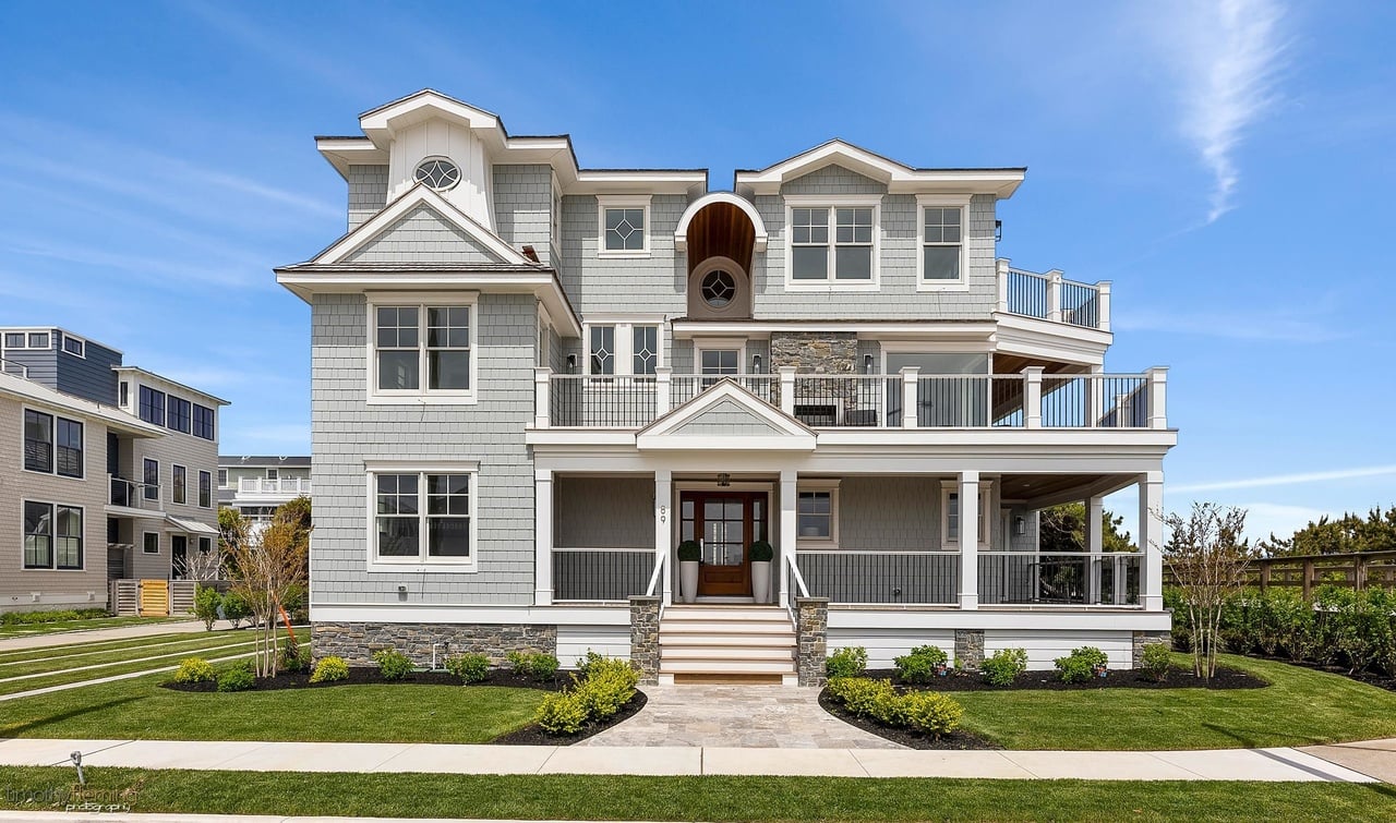 Front exterior of a stylish multi-story New Jersey home with wraparound porches, balconies, stone detailing, and landscaped yard.