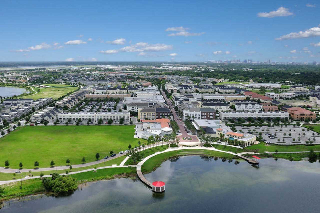 Aerial view of Baldwin Park with a lakeside promenade, green lawn, and neighborhood buildings.
