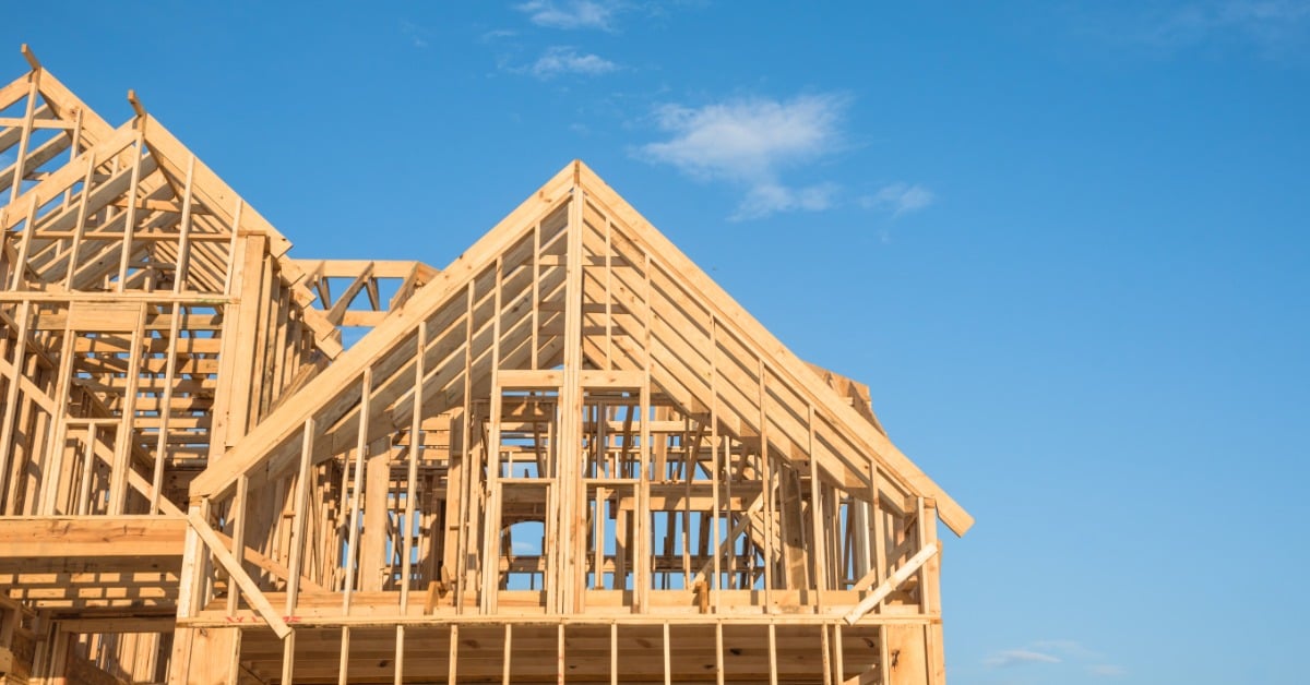 A close-up on the second floor of an unfinished house under construction against a clear blue sky on a sunny day.