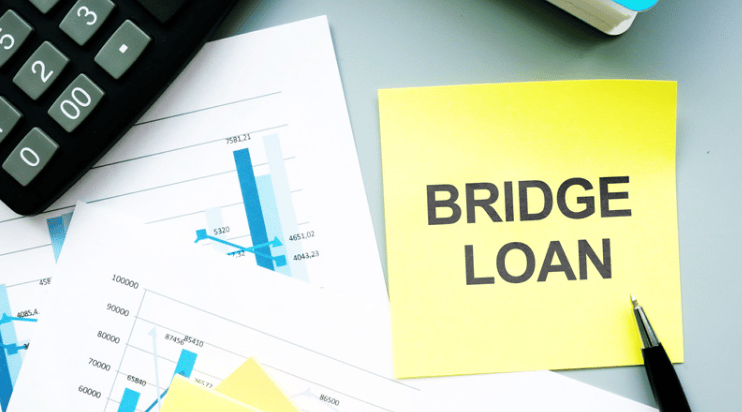 Bridge loan note beside financial charts, a calculator, and a pen.