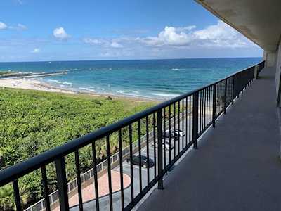 Balcony overlooking the Atlantic Ocean, with a black railing and coastal greenery below.