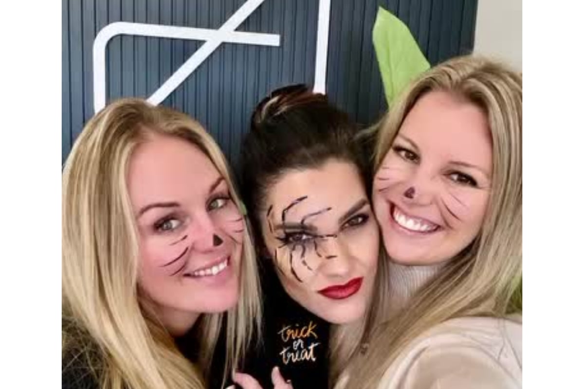 Coastal Living Collective team smile for a selfie in festive makeup and Halloween costumes, posing closely for the camera.