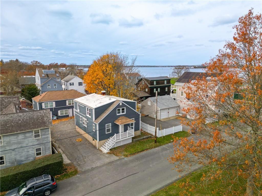 Aerial view of homes near the water, framed by orange autumn foliage.