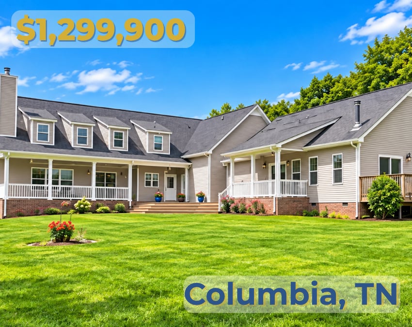 Large beige home with dormer windows, covered porch, brick accents, and a broad green lawn.