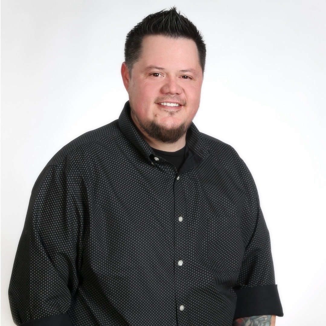 Christopher Paul Turner in a black patterned shirt against a white background.
