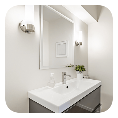 Modern bathroom vanity with a white sink, large mirror, and wall sconces.