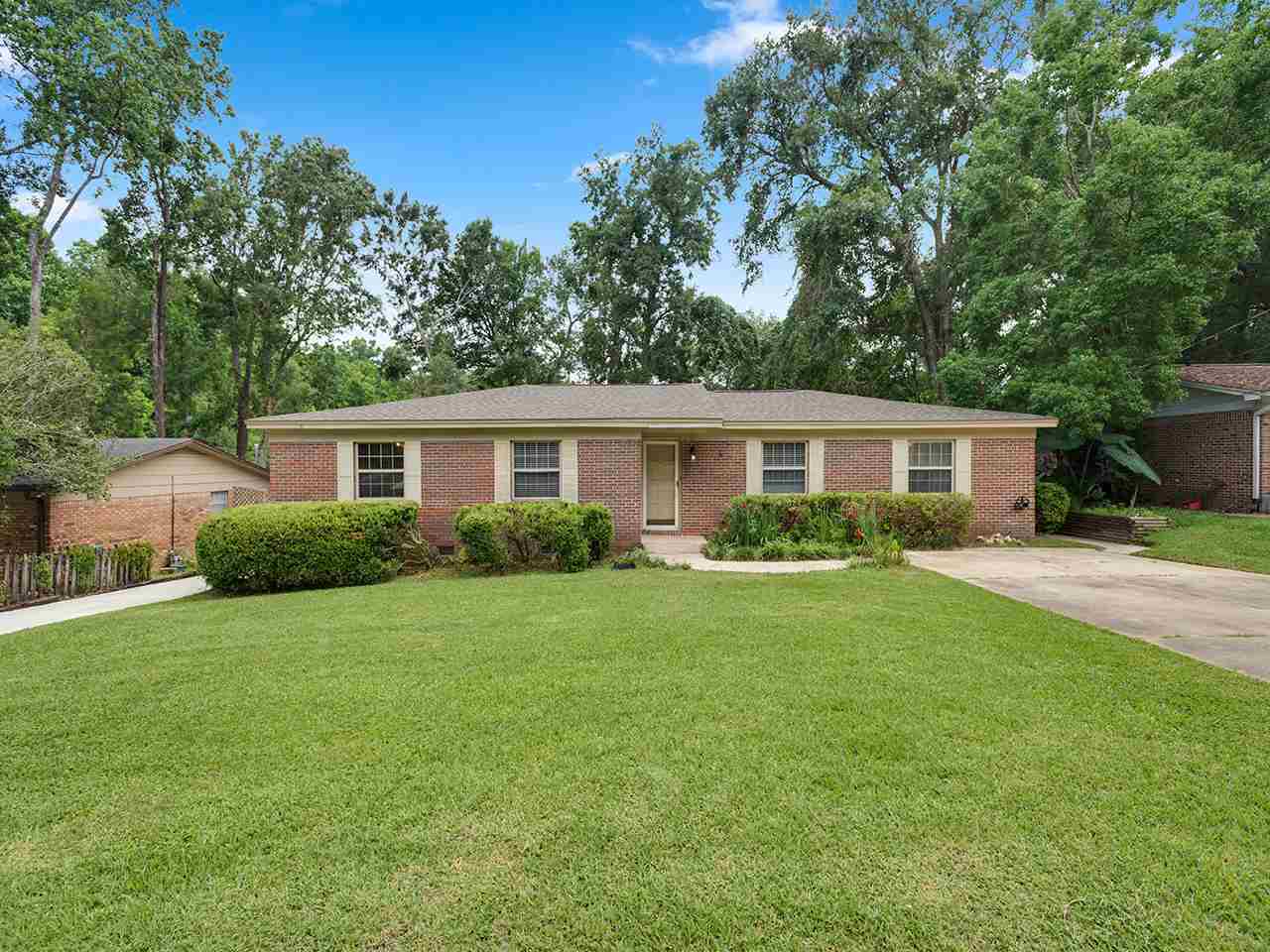 A brick home surrounded by lush green grass and trees, creating a serene and inviting outdoor environment.