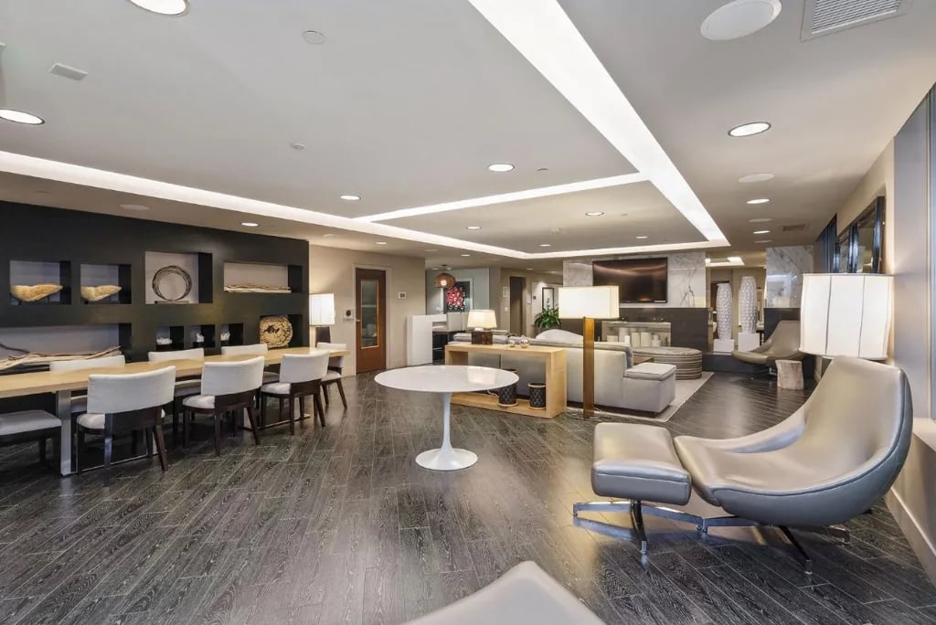 A large, modern community lounge in the Madrone building with a long dining table, seating area, and stylish contemporary furnishings.