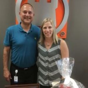 A man and woman pose together beside a wrapped gift basket.