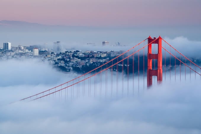 Golden Gate Bridge towers rising above thick fog blanketing San Francisco