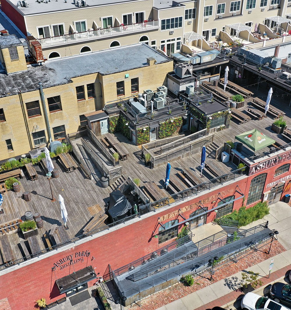 Aerial view of a brick commercial building with a spacious rooftop deck and outdoor seating.