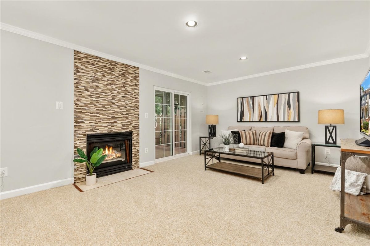 Living room with a lit fireplace, mosaic tile accent wall, and beige sofa.