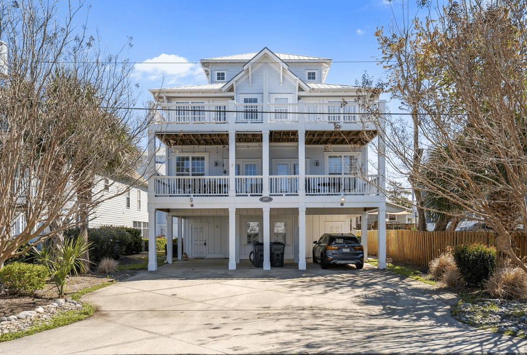 Coastal-style duplex with stacked covered balconies and a wide driveway.