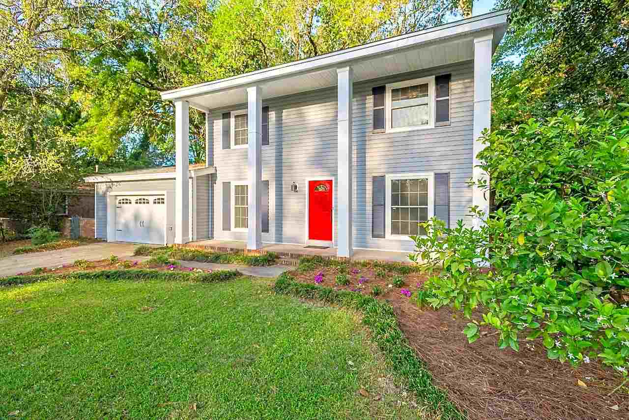 A charming home featuring a vibrant red door complemented by elegant white trim.