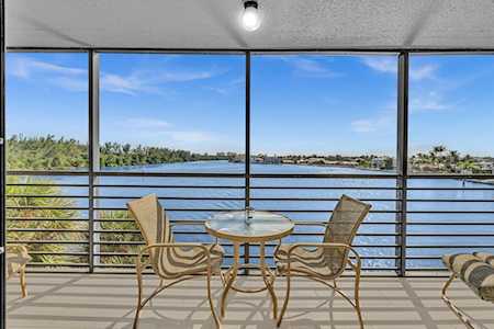 Covered balcony with a café table and chairs overlooking a calm waterway.